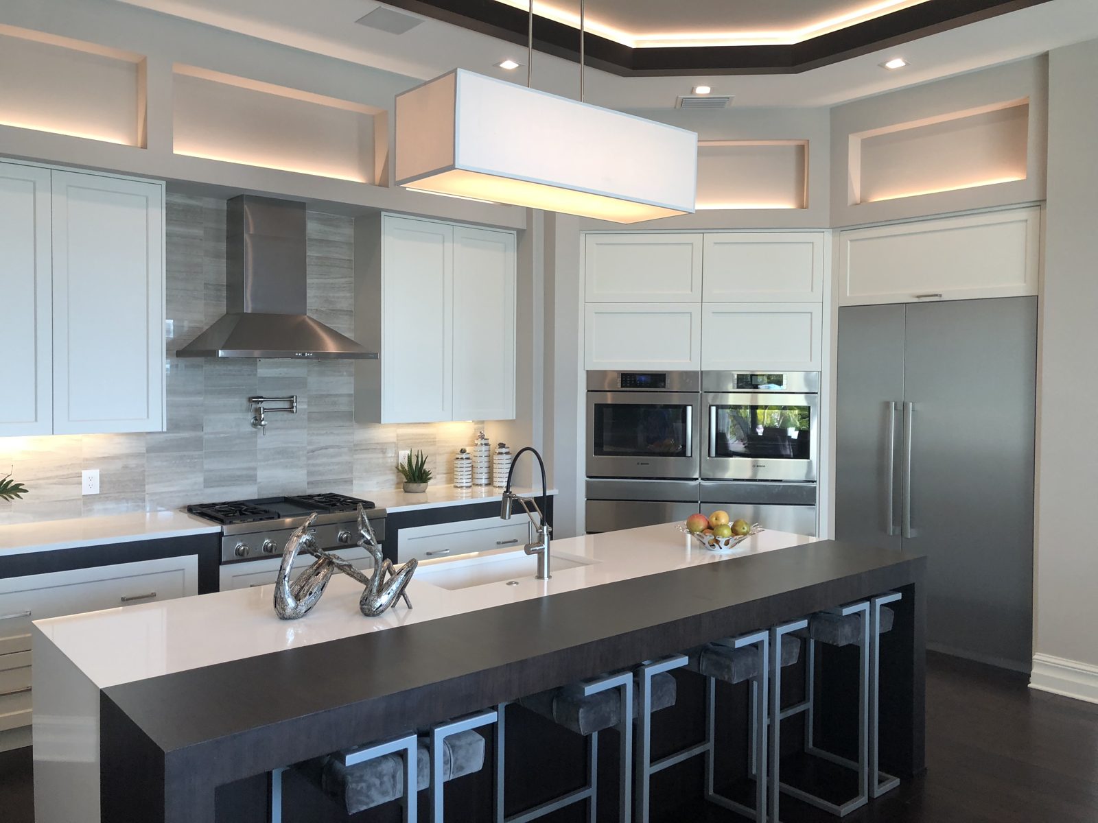 White shaker kitchen with dark waterfall island and quartz countertops