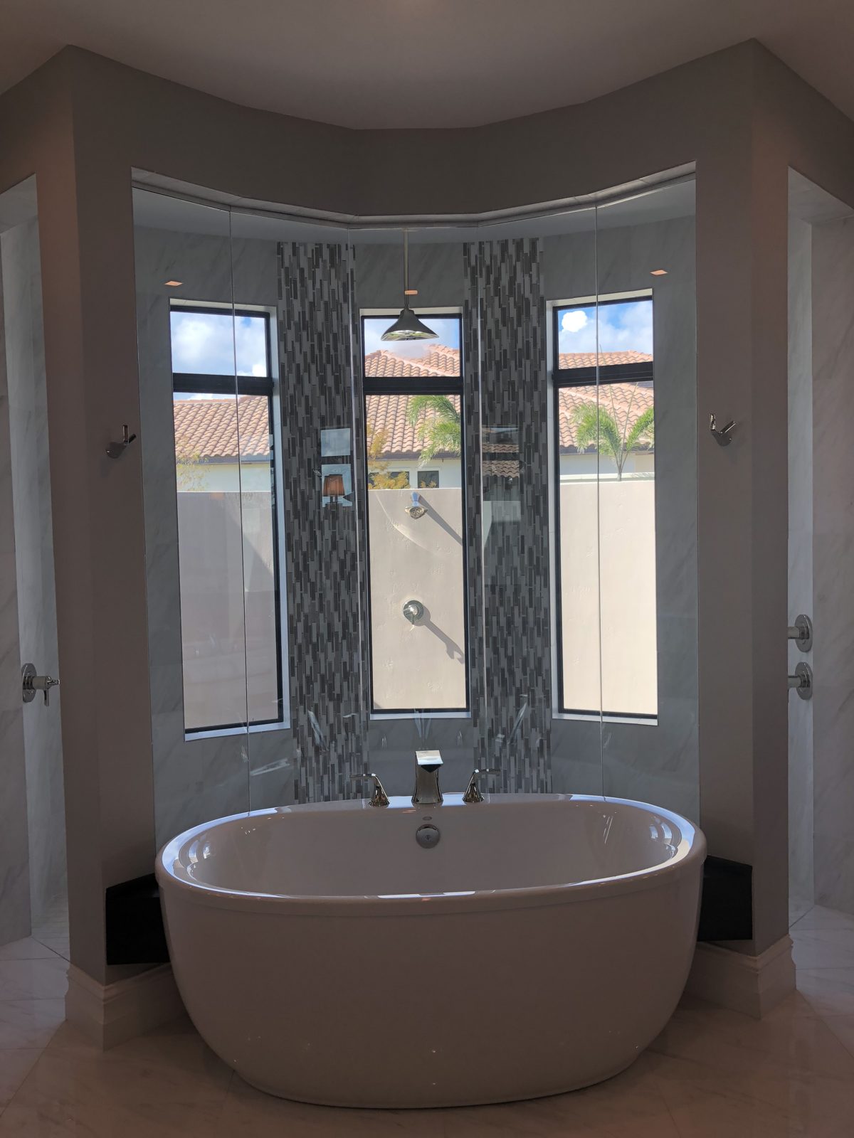 Freestanding soaking tub set in a window bay with mosaic tile accents